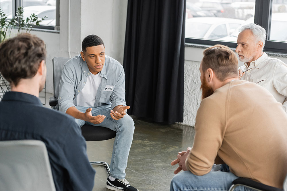 man with alcohol addiction sharing problem during group therapy session